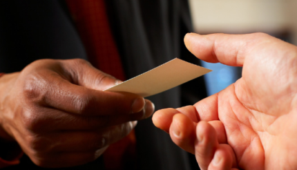 A hand passing a business card to another during networking